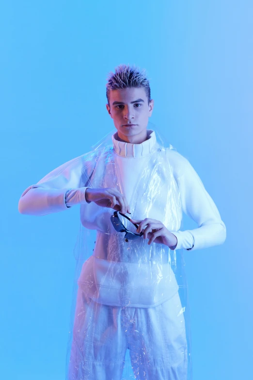 a man standing in front of a blue background, an album cover, inspired by Kristian Kreković, white clothing, covered in circuitry, at a fashion shoot, official store photo