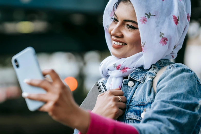 a close up of a person holding a cell phone, a picture, hurufiyya, wearing a head scarf, looking happy, gen z, dynamic scene