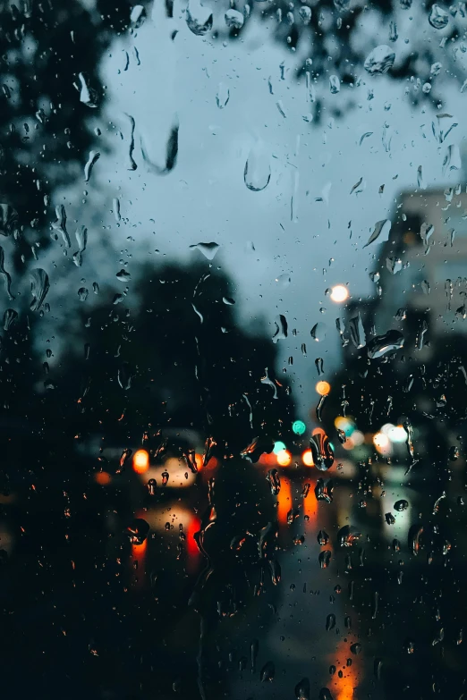 a view of a city through a rainy window, an album cover, unsplash contest winner, headlights turned on, humid evening, trending photo, tear drops