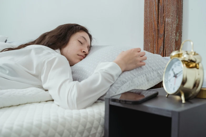 a woman laying in bed next to an alarm clock, trending on pexels, hurufiyya, resting on a pillow, right hand side profile, grey, large head