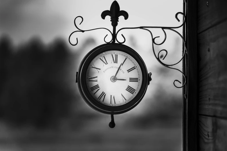 a clock hanging from the side of a building, a black and white photo, pexels, baroque, square, end of the day, made of wrought iron, bokeh. i