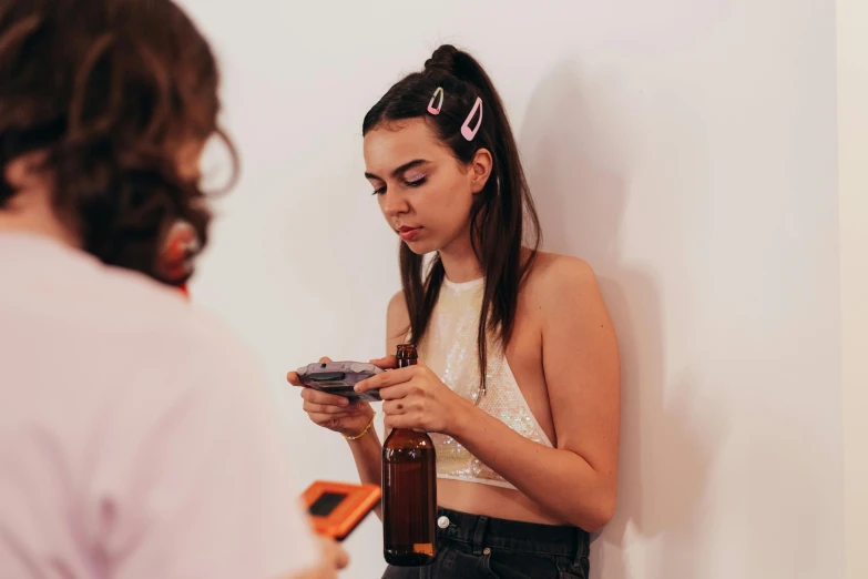a woman standing next to a wall looking at her cell phone, a hyperrealistic painting, by Olivia Peguero, trending on pexels, hyperrealism, drinking cough syrup, college party, bralette, a group of people