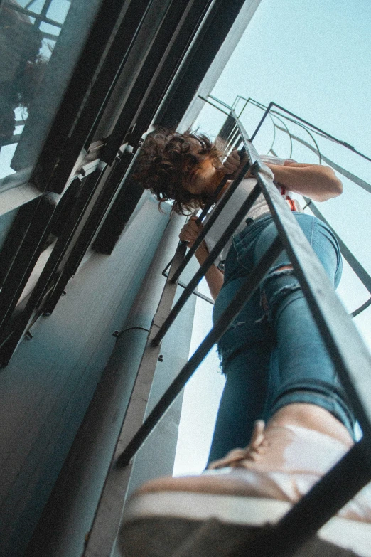 a woman standing on top of a metal staircase, pexels contest winner, wearing blue jean overalls, standing on the mast, zac retz, gif