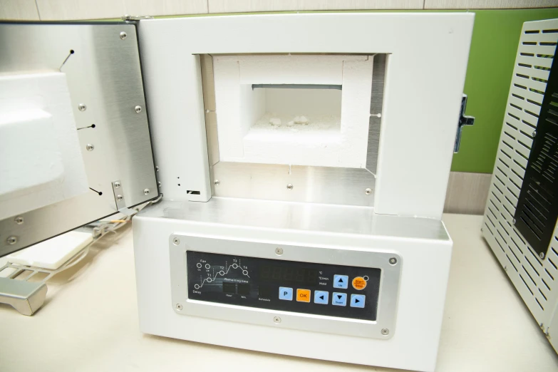a white machine sitting on top of a counter, an etching, plasma display, inside its box, molten plastic, green