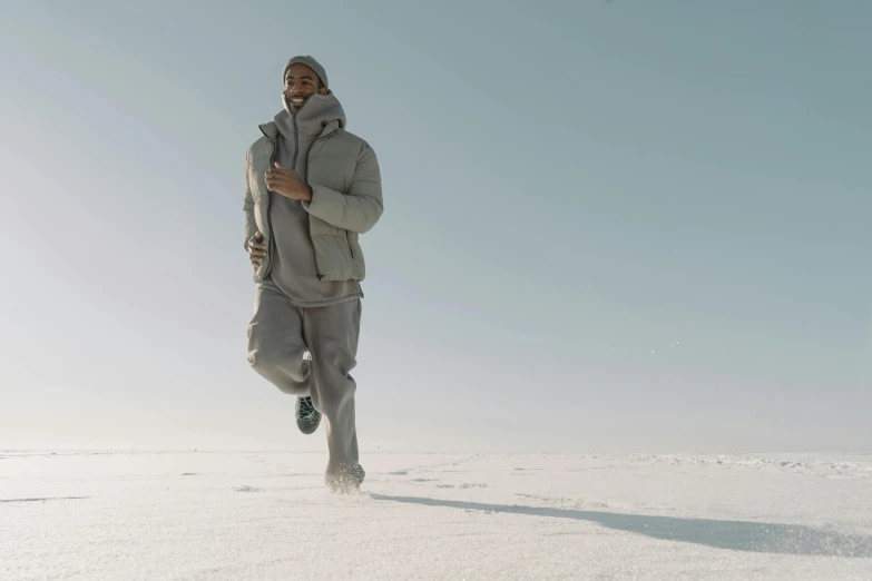 a man running across a snow covered field, inspired by Salomon van Abbé, unsplash contest winner, hurufiyya, chappie in an adidas track suit, ignant, with grey skin, mkbhd