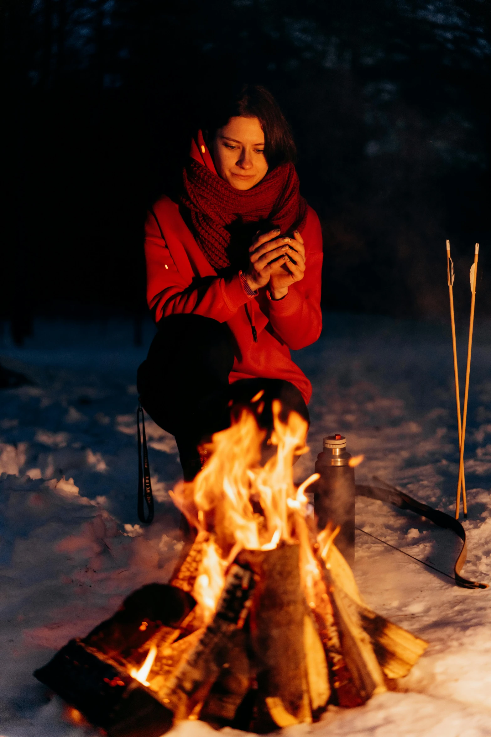 a woman sitting next to a fire in the snow, app, rituals, connectivity, maroon