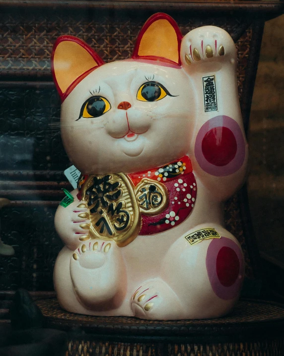 a figurine of a cat sitting on a chair, a statue, pexels contest winner, toyism, wearing a red cheongsam, animal - shaped bread, thumbnail, south east asian with round face