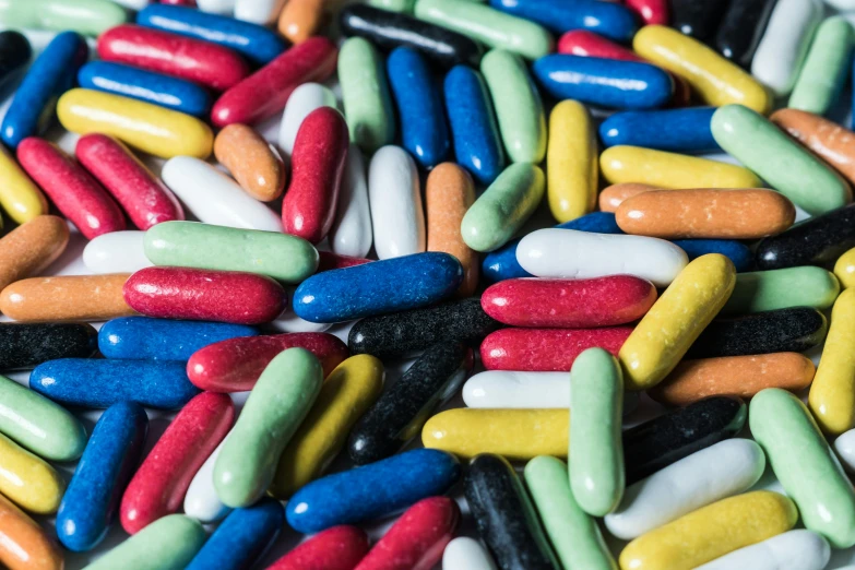 a pile of colorful pills sitting on top of a table, inspired by Damien Hirst, unsplash, candy worms, “ iron bark, rainbow coloured rockets, 15081959 21121991 01012000 4k