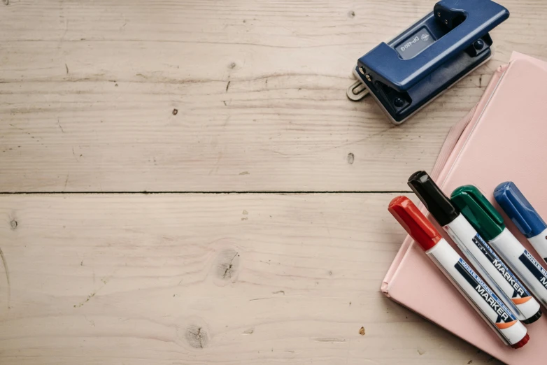 a pink notebook sitting on top of a wooden table, various items, thumbnail, whiteboards, a wooden