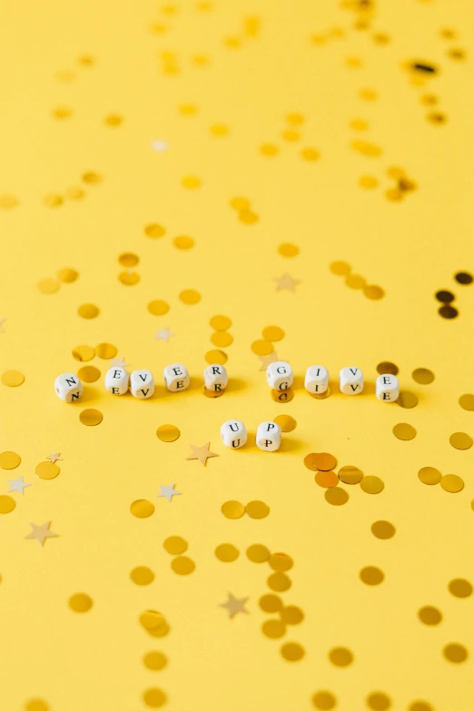 a bunch of dices sitting on top of a table, by Nicolette Macnamara, trending on pexels, uppercase letter, silver and yellow color scheme, tiny stars, minn