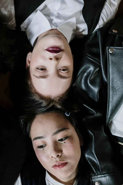 a couple of women laying on top of each other, by Cosmo Alexander, trending on pexels, renaissance, androgynous face, leather jackets, clear symmetrical face, asian features