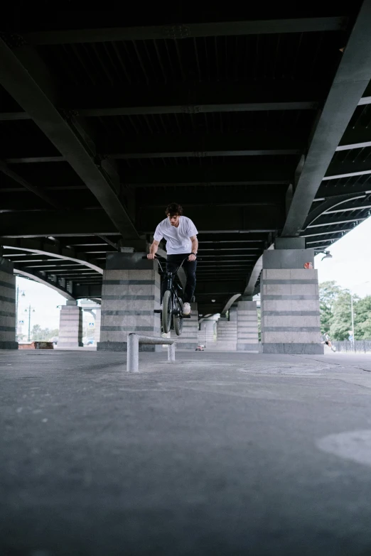 a man flying through the air while riding a skateboard, unsplash, concrete pillars, bicycle, low quality footage, square