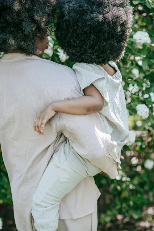 a man carrying a little girl in his arms, pexels contest winner, renaissance, with soft bushes, african american woman, rear shot, soft muted colors