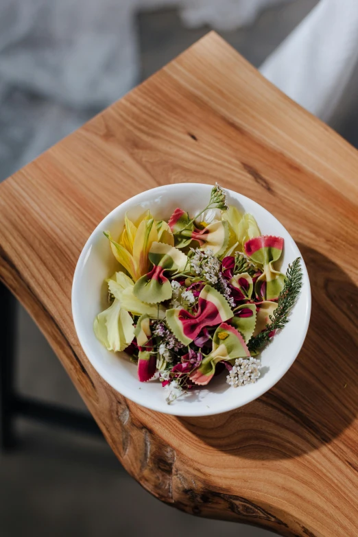 a bowl of food sitting on top of a wooden table, flower petals, lush botany, crisp clean shapes, infused