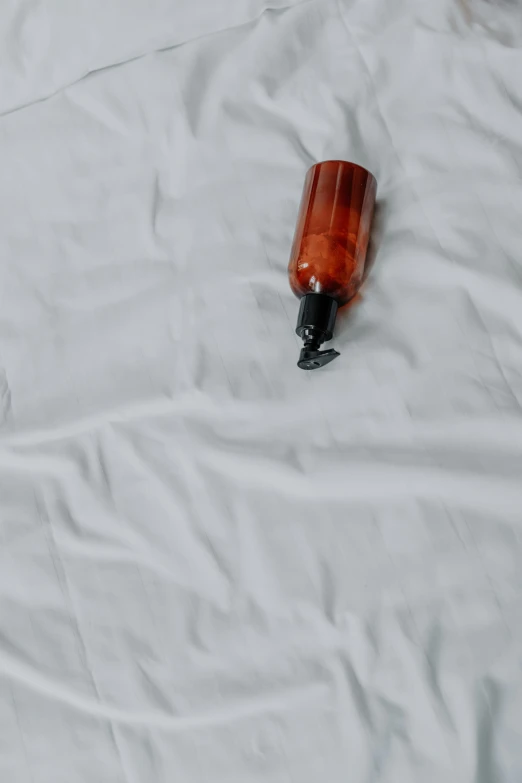 a bottle sitting on top of a white sheet, profile image, no text, orange body, thumbnail