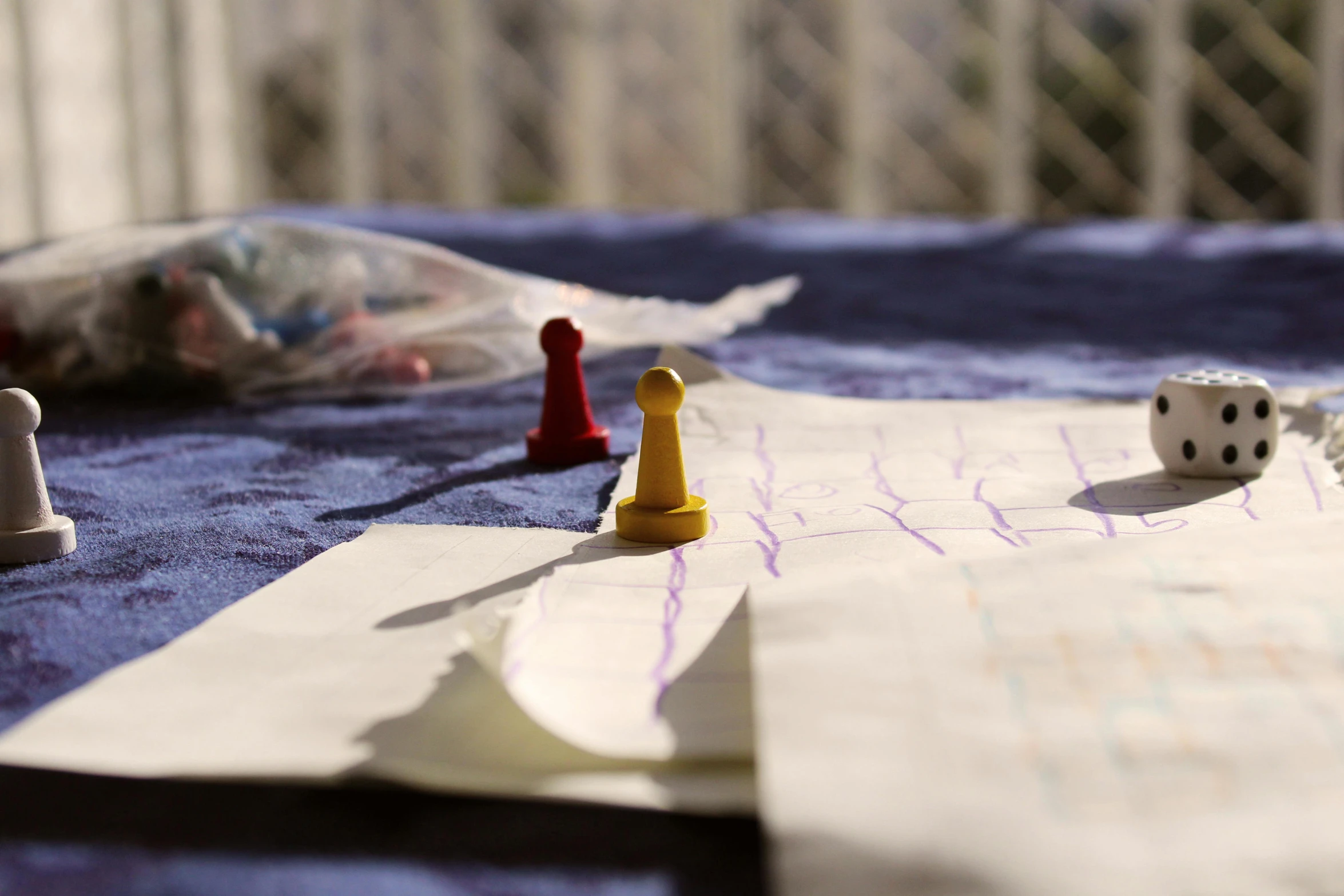 a couple of pieces of paper sitting on top of a table, a child's drawing, by Romain brook, chess pawn, purple and yellow, candid photograph, sunny day