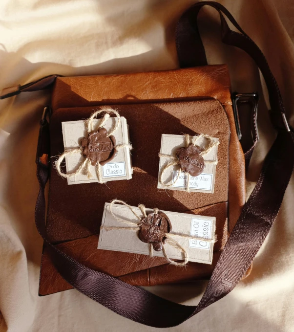 a brown bag sitting on top of a bed, clay amulets, botanical herbarium paper, wrapped in leather straps, singularity sculpted �ー etsy