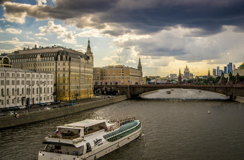 a boat traveling down a river next to tall buildings, pexels contest winner, german romanticism, kremlin, clouds around, soviet style, thumbnail