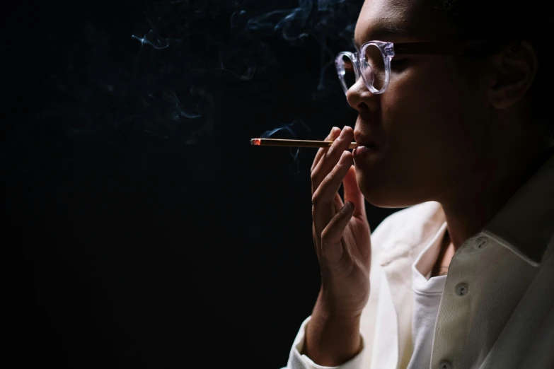 a woman in glasses smokes a cigarette, trending on pexels, dark skinned, late night, androgynous person, marijuana smoke