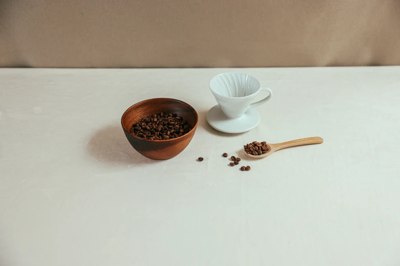 a bowl of coffee beans next to a wooden spoon, inspired by Ceferí Olivé, minimalism, next to a cup, top and side view, handcrafted, small scale