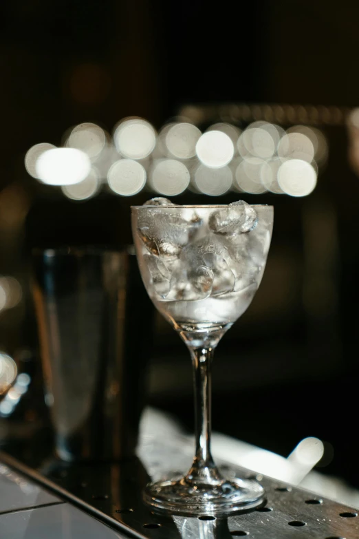 a glass of water sitting on top of a bar, by Ndoc Martini, renaissance, close up of single sugar crystal, lights on, silver mist, polished