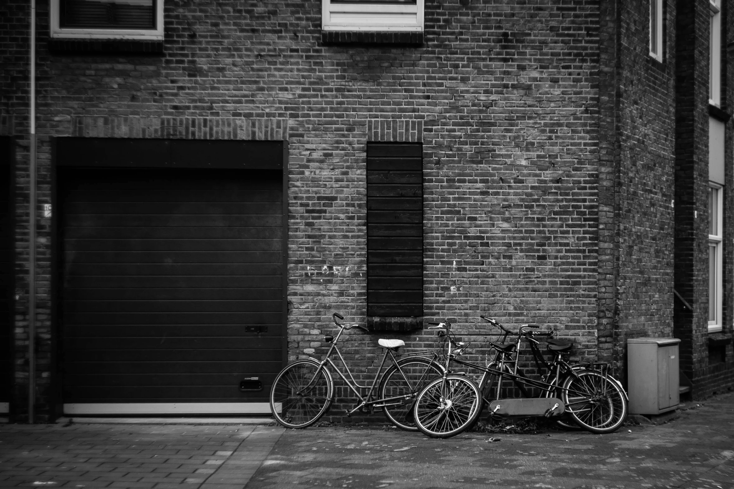 a couple of bikes parked in front of a building, by Daniel Seghers, black an white, bricks, profile image, 3 doors