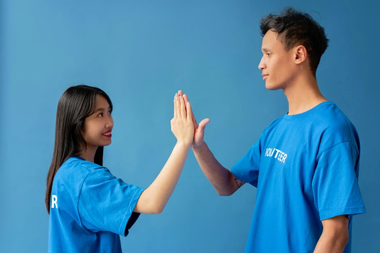 a man and a woman giving each other a high five, pexels contest winner, aestheticism, blue uniform, asian girl, avatar image, wearing a t-shirt