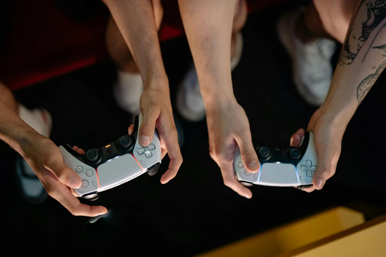 two people holding video game controllers in their hands, by Julia Pishtar, unsplash, playstation 5 graphics, wide high angle view, style game square enix life, photographed for reuters