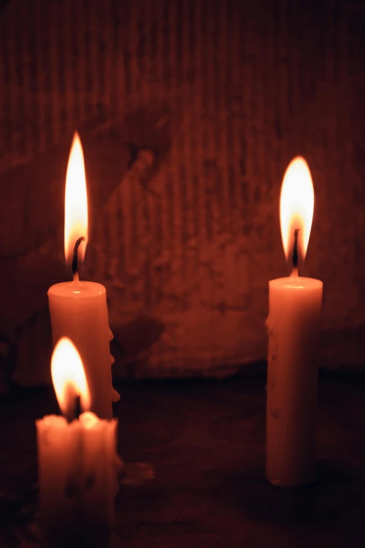 three lit candles sitting on top of a wooden table, an album cover, inspired by Elsa Bleda, flickr, headshot, ignant, candlelit catacombs, profile image