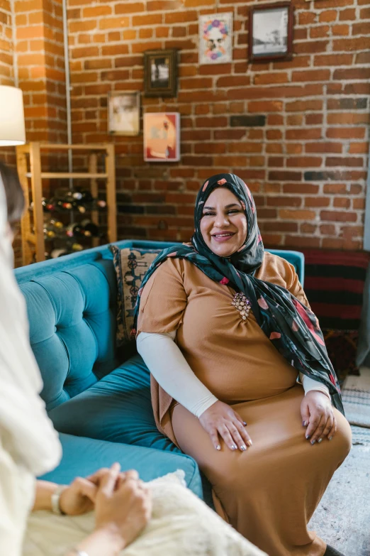 a woman sitting on a couch talking to another woman, hurufiyya, maternity feeling, hijab, plus-sized, curated collections