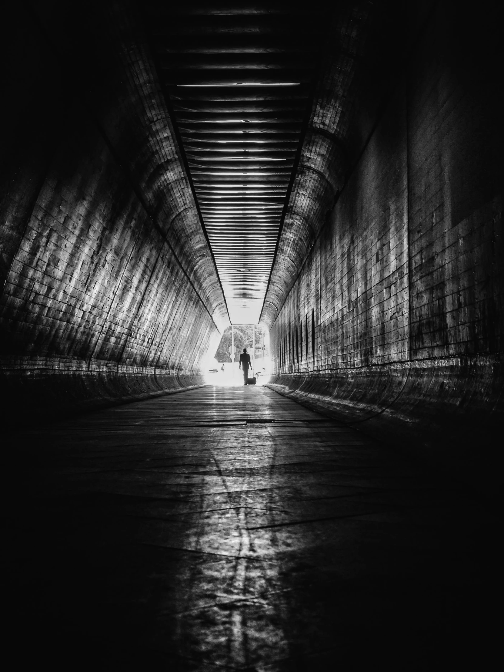 a black and white photo of a person walking through a tunnel, by Daniel Gelon, paul barson, 5 0 0 px, by greg rutkowski, ilustration