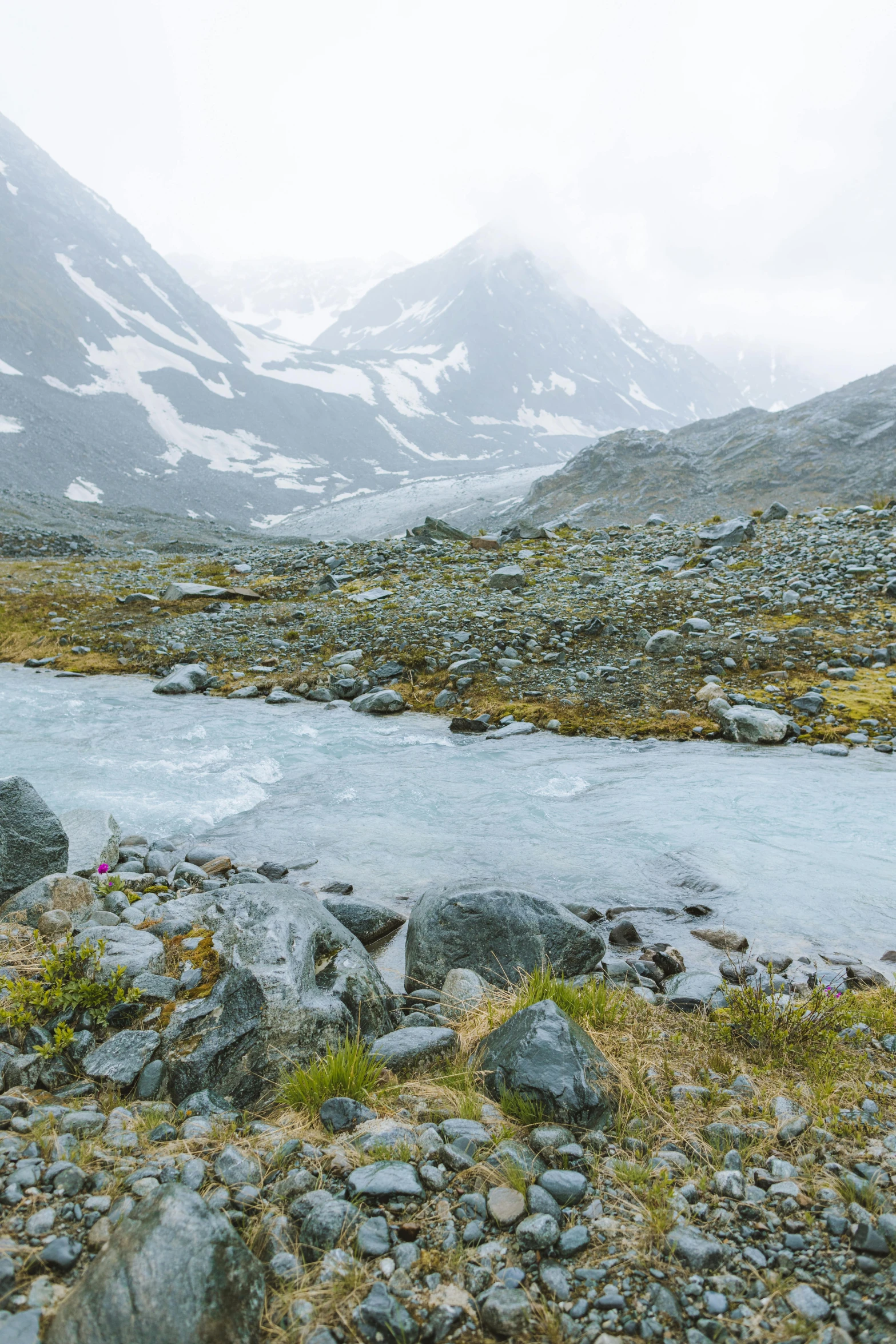 a man standing on top of a rocky field next to a body of water, a picture, inspired by Werner Andermatt, trending on unsplash, in an icy river, glacier landscape, photo 4k, small stream