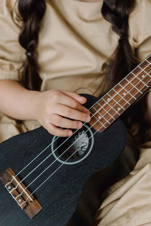 a little girl that is sitting down with a guitar, ukulele, zoomed in, curated collections, thumbnail