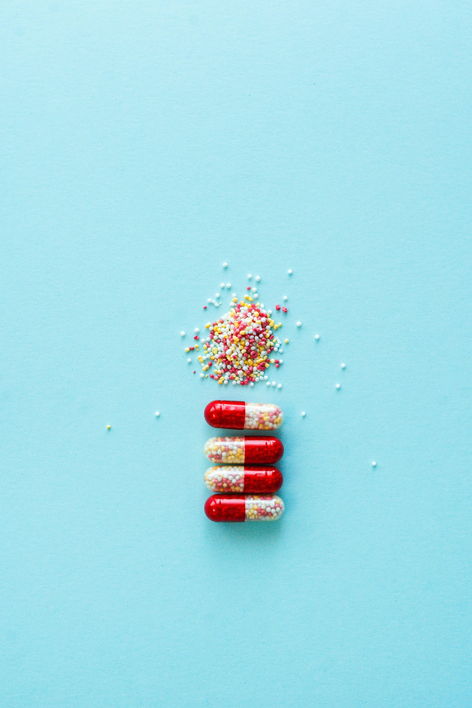 two pills and sprinkles on a blue surface, a picture, pexels, process art, crimson themed, pharmacy, full body image, multiple stories