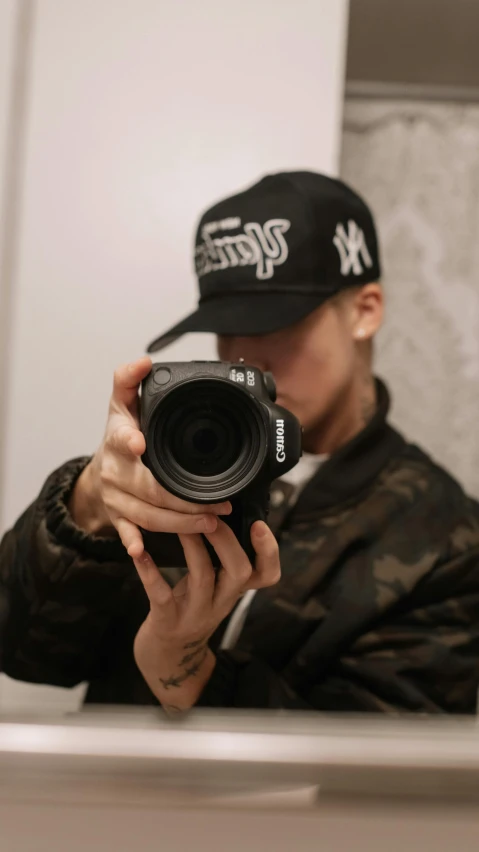 a man taking a picture of himself in the mirror, by Robbie Trevino, pexels contest winner, graffiti, black cap, headshot profile picture, shot with a canon, mrbeast