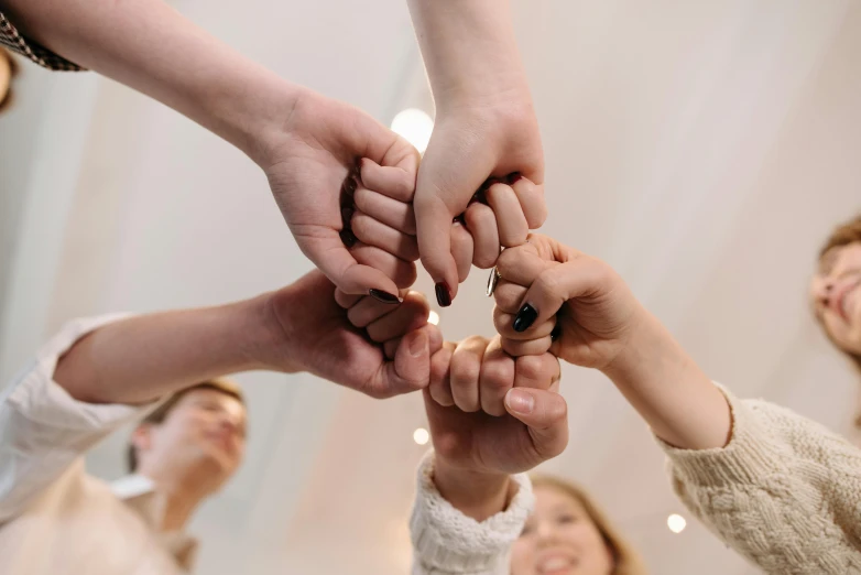 a group of people putting their hands together, by Adam Marczyński, trending on pexels, holding a wand, in a fighting pose, nursing, we can do it