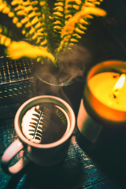 a cup of coffee and a candle on a table, inspired by Elsa Bleda, in a deep lush jungle at night, yellow mist, lo-fi, high angle shot