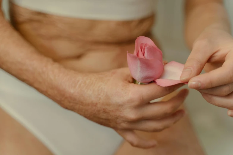 a close up of a person holding a flower, chiseled abs, pastel pink skin tone, serving body, flirting