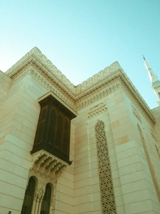 a large white building with a clock tower in the background, by Riad Beyrouti, pexels contest winner, hurufiyya, yellow windows and details, sunfaded, minarets, taken in the late 2000s