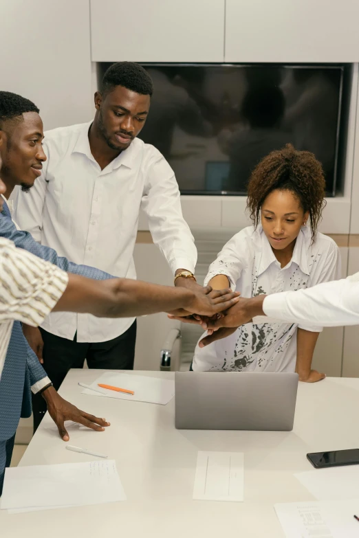 a group of people standing around a table with a laptop, pexels contest winner, black arts movement, mechanics, reaching out to each other, competition winning, kano)