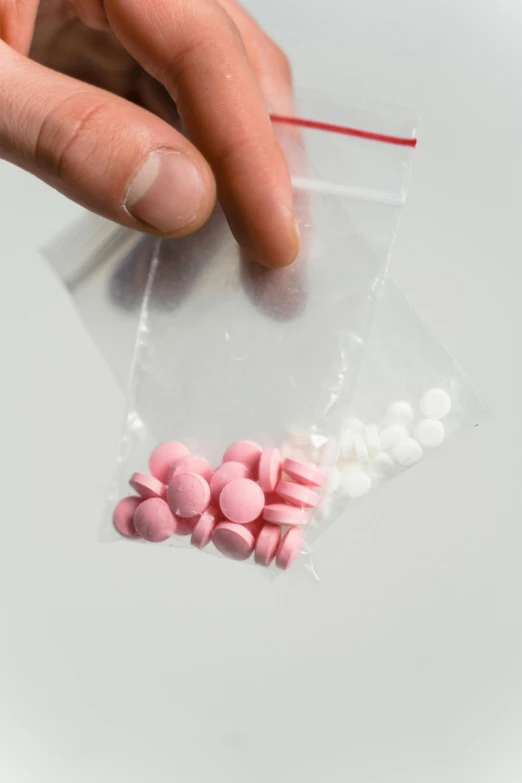 a close up of a person holding a bag of pills, by Ryan Pancoast, antipodeans, portrait of a pink gang, made of candy, high quality material bssrdf, criminals