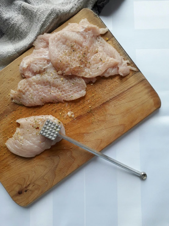 a piece of chicken sitting on top of a wooden cutting board, spatula, grey, stippled, dipstick tail