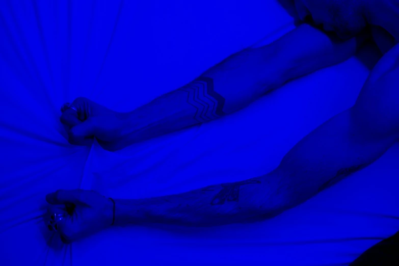 a close up of a person holding an umbrella, a tattoo, inspired by Yves Klein, unsplash, digital art, laying in bed, illuminated blue neon lines, tribal tattoos right arm sleeve, laying on a bed