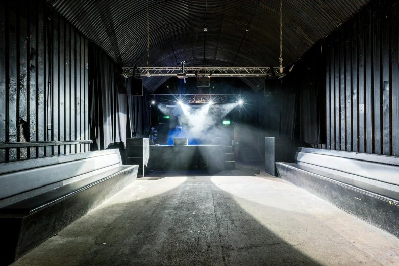 a stage with smoke coming out of it, by Nick Fudge, unsplash, light and space, underground facility, looking towards camera, mini amphitheatre, back rooms