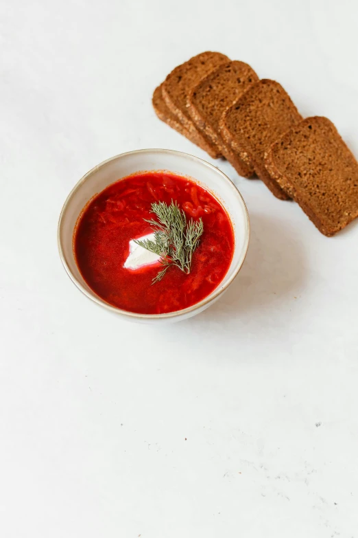 a bowl of soup and some bread on a table, a portrait, unsplash, white red, square, metallic red, set against a white background