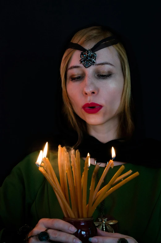 a woman blowing out candles on a cake, an album cover, inspired by Master of the Legend of Saint Lucy, unsplash, renaissance, wearing sith hood, anna nikonova aka newmilky, candlelight, movie photo