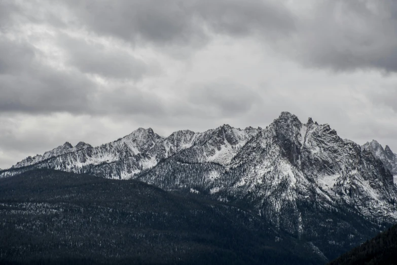 a black and white photo of a mountain range, by Matthias Weischer, pexels contest winner, overcast gray skies, winter storm, 4 k hd wallpapear, spires