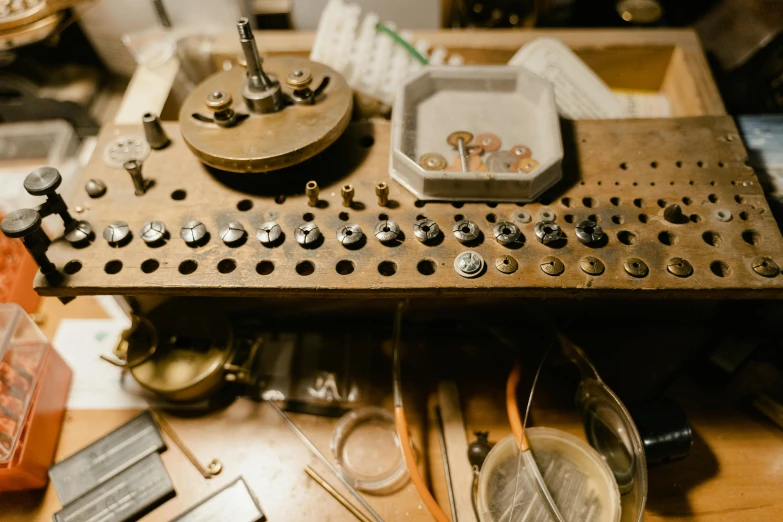 a machine sitting on top of a wooden table, unsplash, assemblage, metallic buttons, scientific instruments, jewelry, ivory and copper