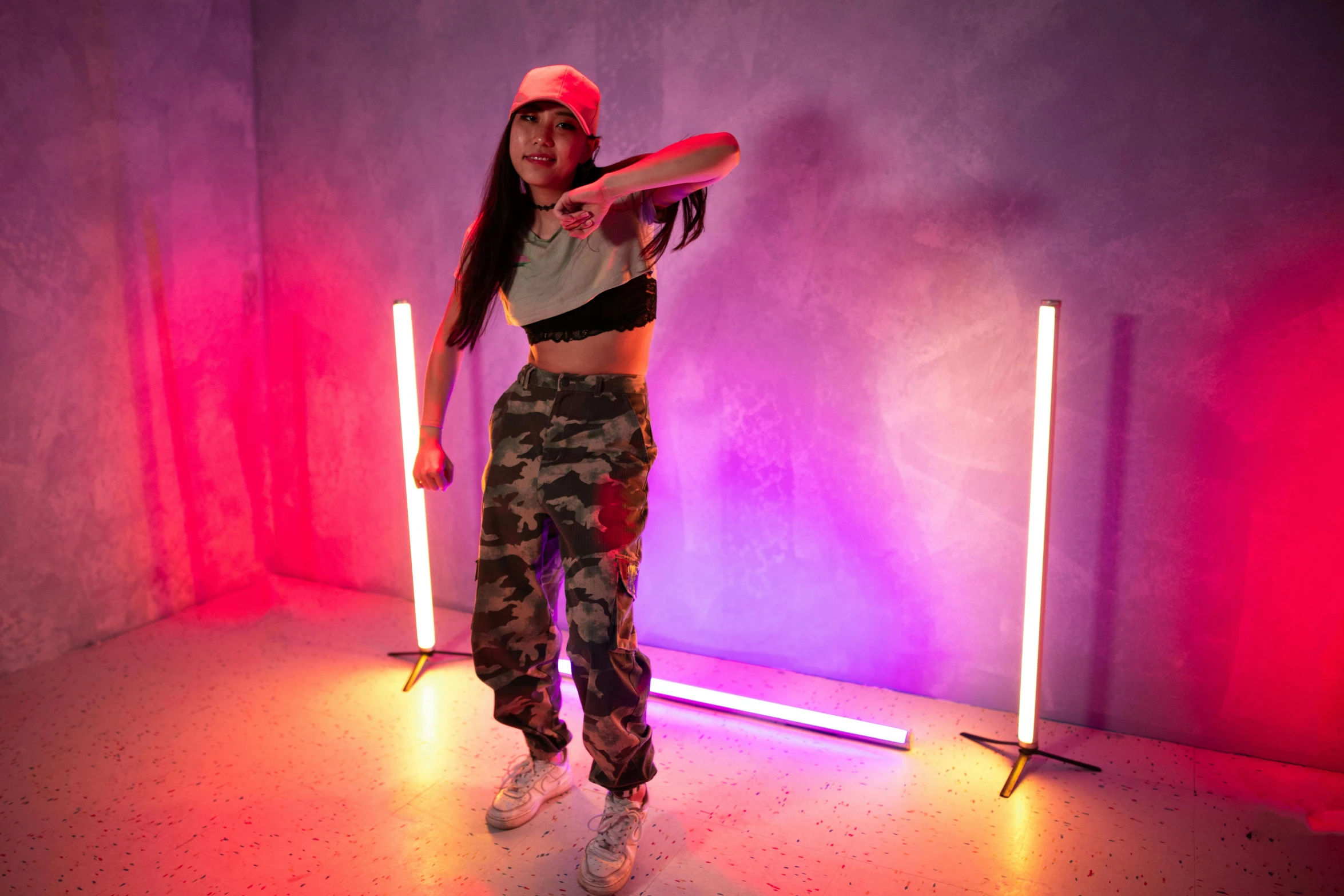 a woman standing in a room holding a frisbee, by Robbie Trevino, trending on pexels, graffiti, led light strips, chrome dance pole, she is wearing streetwear, various poses shooting photos