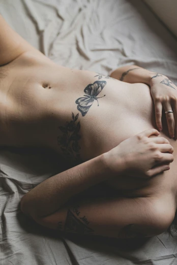 a naked woman laying on a bed next to a window, a tattoo, unsplash contest winner, half-woman half-butterfly, gif, lesbian, her belly button is exposed